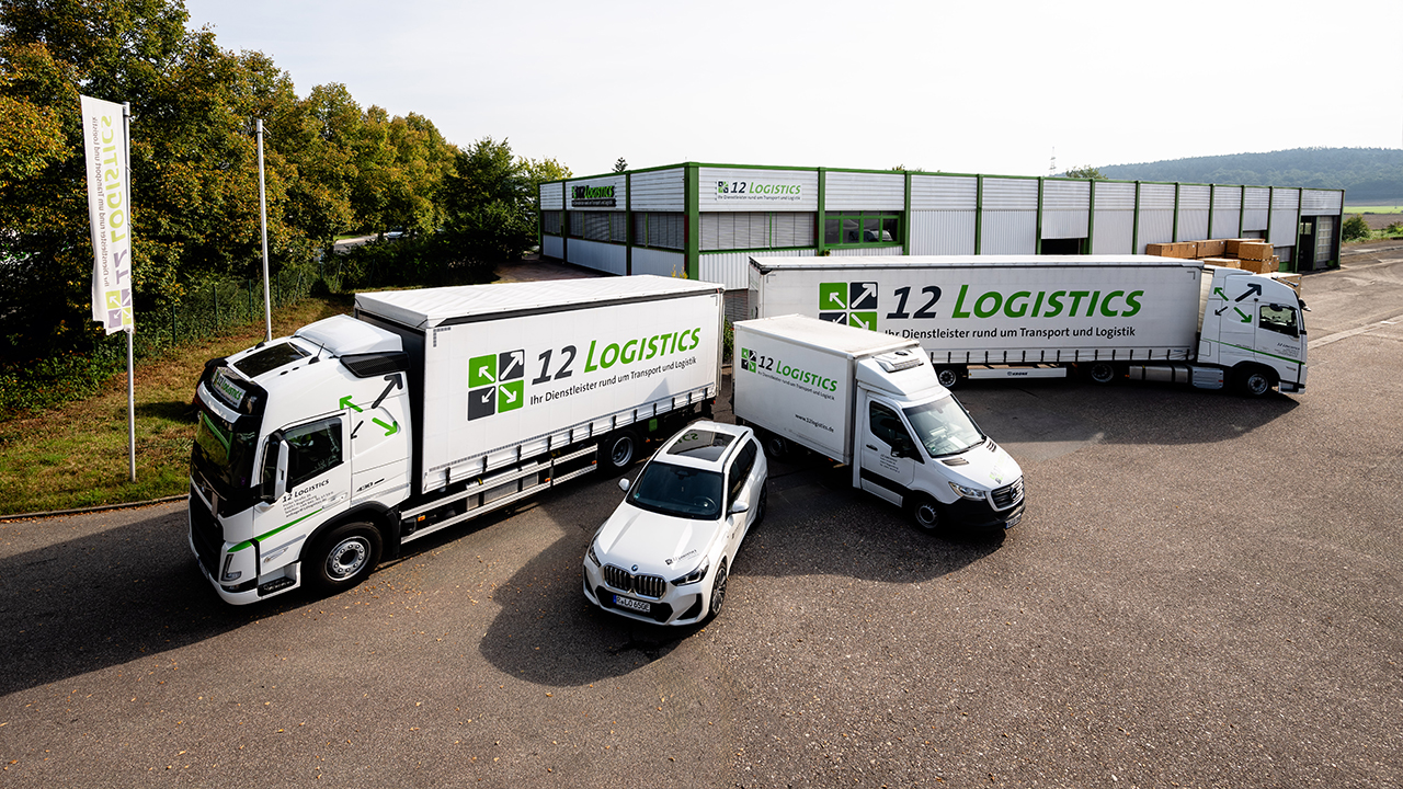 Vier Transportfahrzeuge vor Firmengebäude