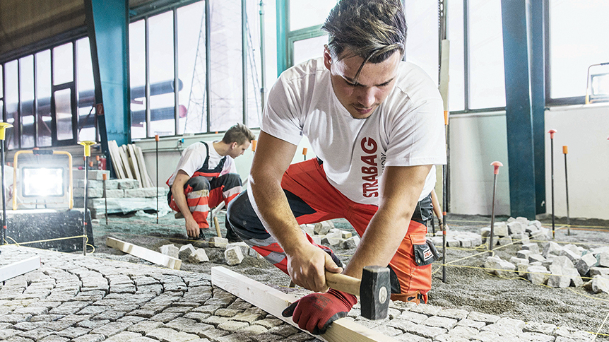 Zwei junge Männer beim Pflastern von Steinen