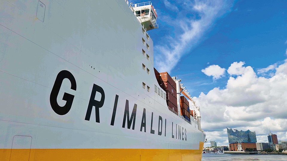 Seitliche Ansicht eines GRIMALDI-Containerschiffs mit der Hamburger Elbphilharmonie im Hintergrund