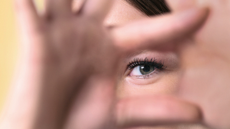 Mensch hält Hände zum Quadrat und schaut mit Auge durch