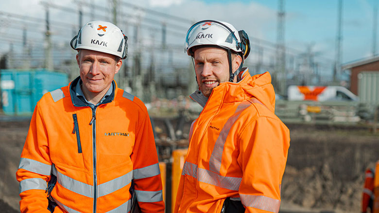 Mitarbeitende Matthäi Bauunternehmen in orangefarbener Schutzkleidung mit Helm