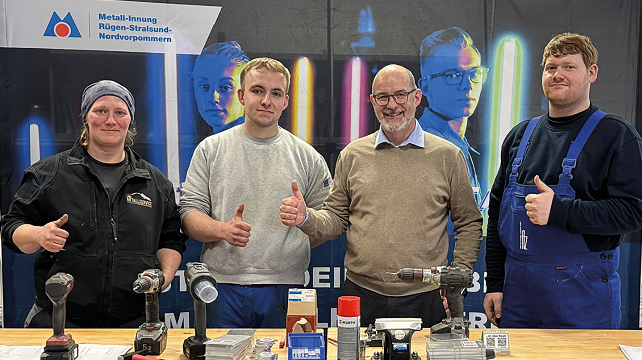 Vier Personen stehen an einem Messestand der Metall-Innung und zeigen die Daumen nach oben