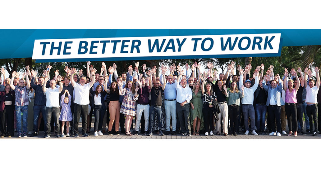 Gruppenfoto am Pool, Banner im Hintergrund mit der Aufschrift: The better way to work