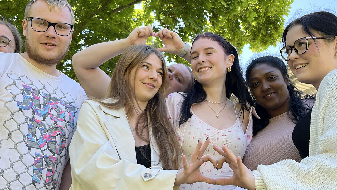 Gruppenbild, zwei Personen formen aus ihren Händen ein Herz.