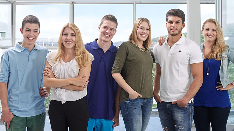 3 junge Männer und 3 junge Frauen stehen nebeneinander und lächeln in die Kamera