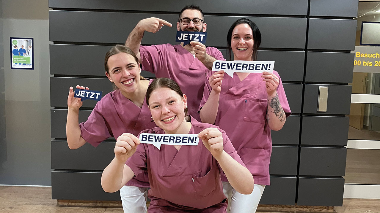 4 Pflegekräfte zeigen kleine Blätter mit "Jetzt" und "Bewerben" hoch.