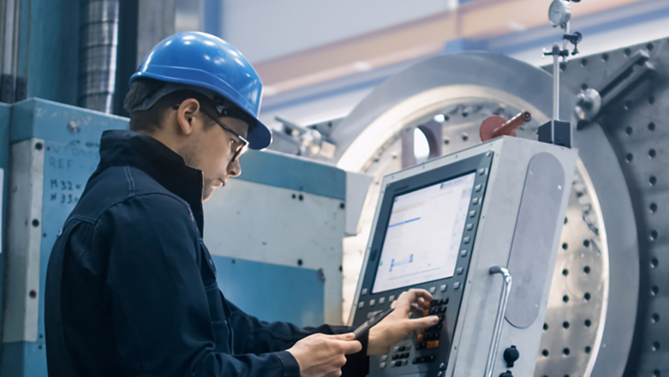 Person mit Schutzhelm bedient eine Maschine