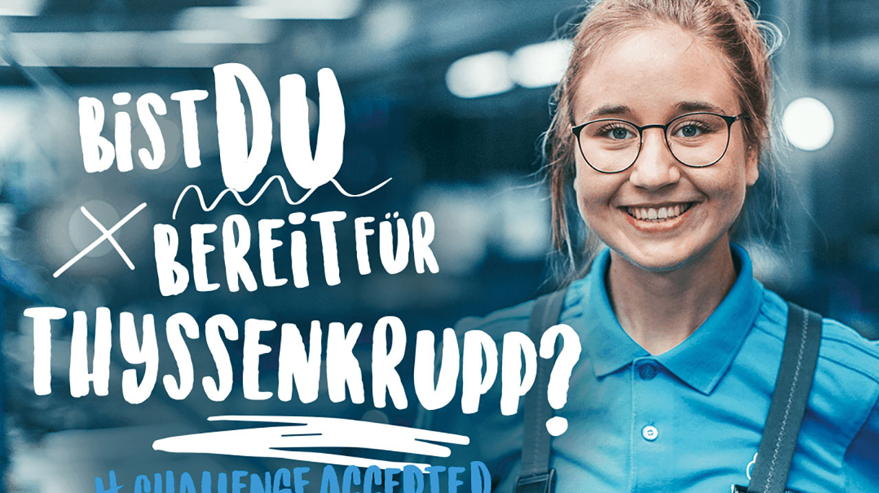 Junges strahlendes Mädchen mit Brille in blauer Latzhose.