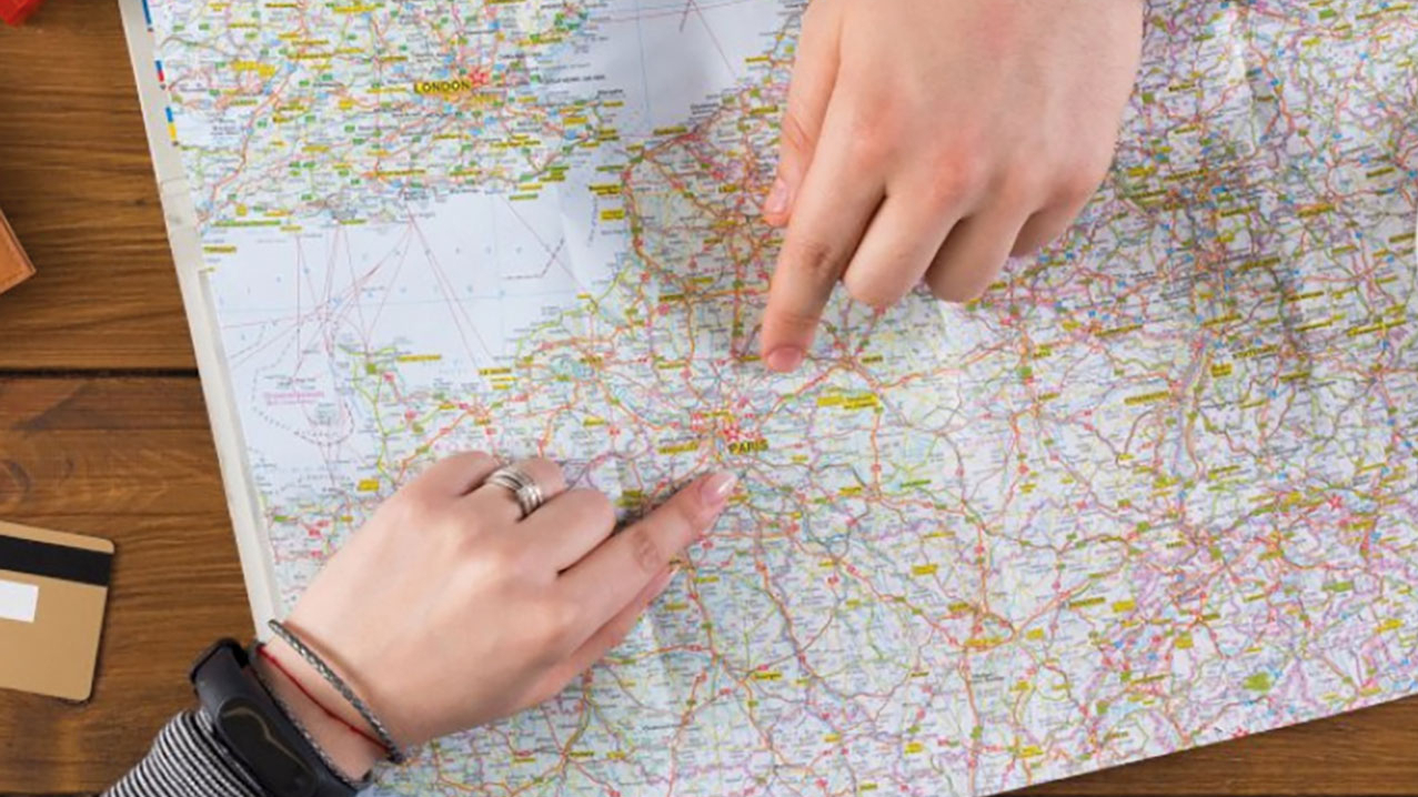 Zwei Zeigefinder zeigen auf einer Staßenkarte auf Paris.