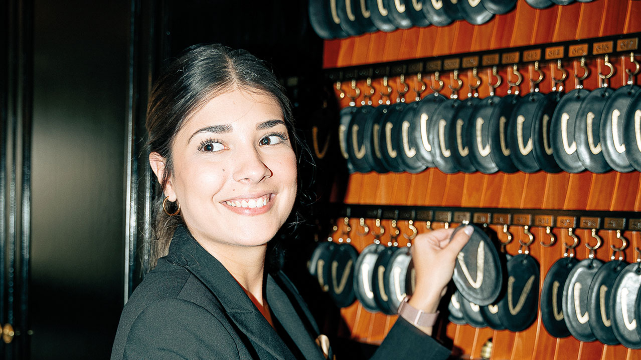 Nette Empfangsmitarbeiterin gibt einen Schlüssel heraus.