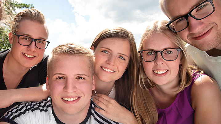 Selfie von sechs jungen lächelnden Menschen bei Sonnenschein