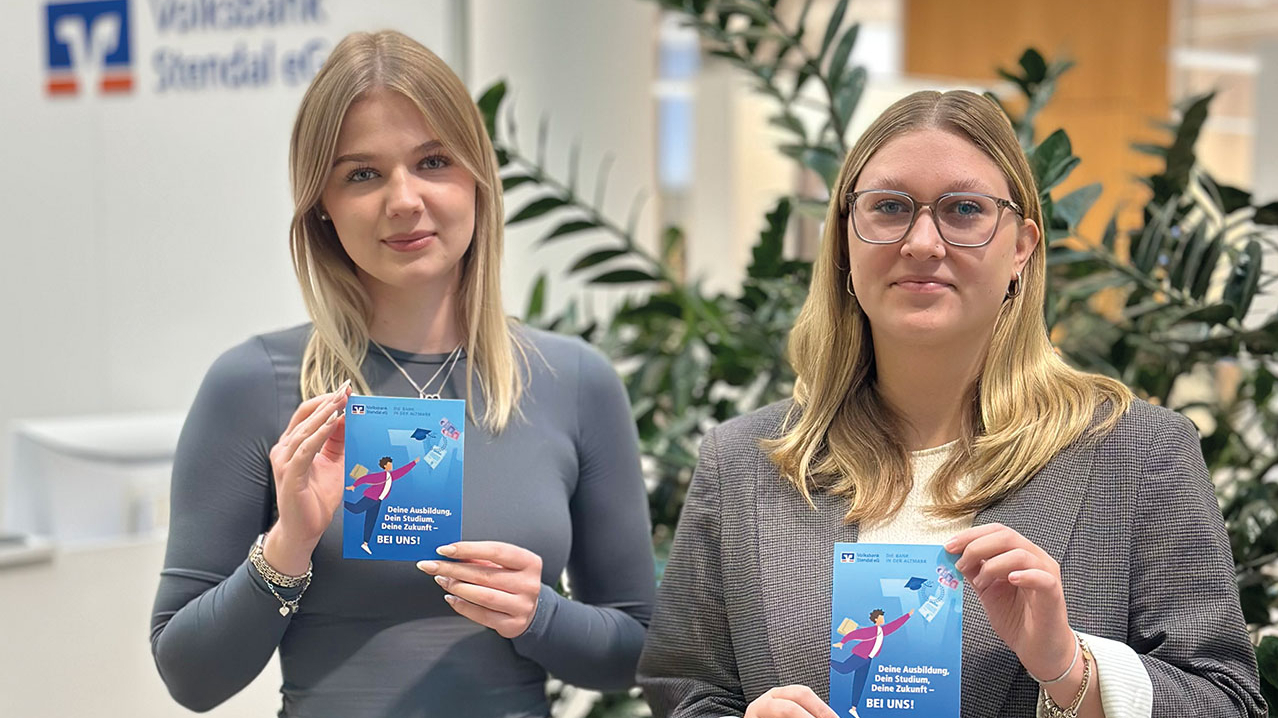 Zwei junge Damen halten einen Werbeflyer der Volksbank in den Händen.