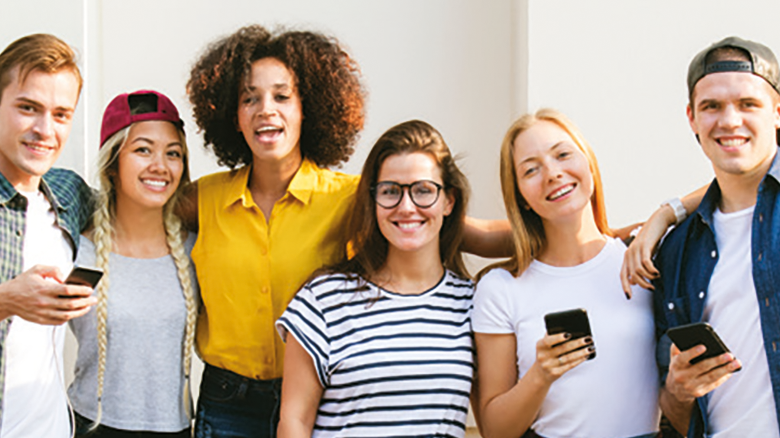 6 sehr fröhliche und bunt angezogene Menschen stehen als Gruppe nebeneinander und lächeln in die Kamera