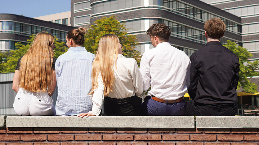 Jugendliche sitzen auf einer Mauer vor Firmengebäude