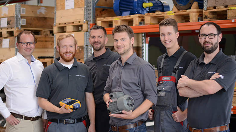 Sechs Mitarbeitende aus verschiedenen Bereichen vor einem Lagerregal