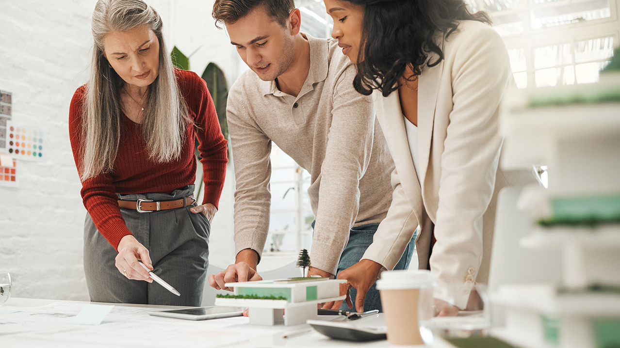 3 Personen stehen gebeugt über einem Tablet