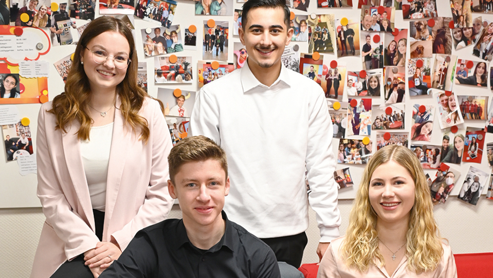 Gruppenbild vor einer Wand mit vielen Fotos