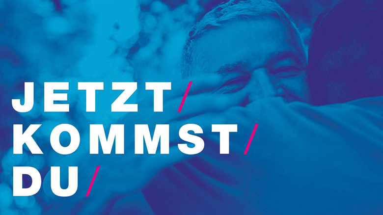 Blau eingefärbtes Bild von zwei Personen, die sich umarmen, Bildaufschrift: Jetzt kommst du