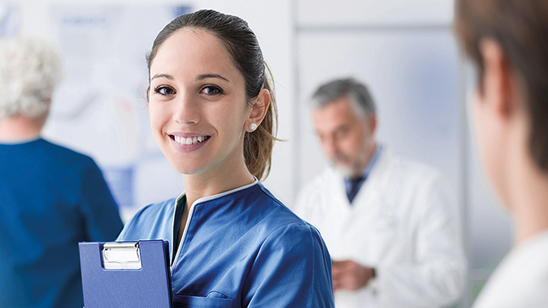Junge Frau im Arztkittel von Kollegen/-innen und Arzt umgeben