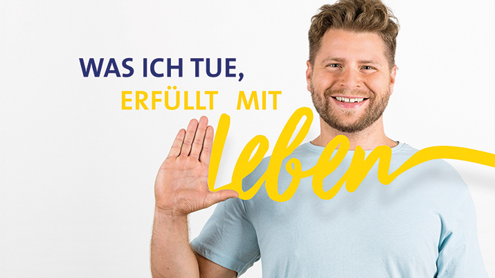 Person lächelt daneben der Slogan "WAS ICH TUE, ERFÜLLT MIT LEBEN".