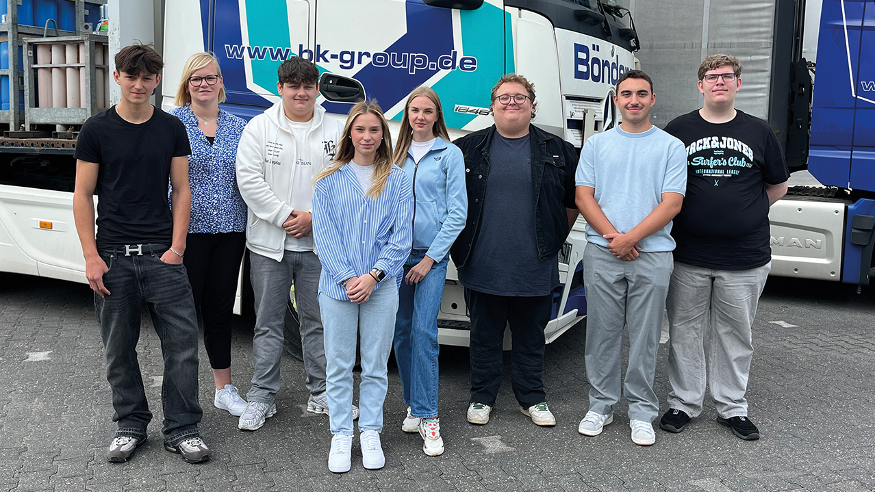 Gruppe junger Menschen vor LKW, die in die Kamera lächeln