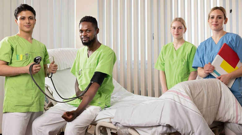 Junge Menschen am Krankenbett in Pfleger- bzw. Krankschwesterkleidung