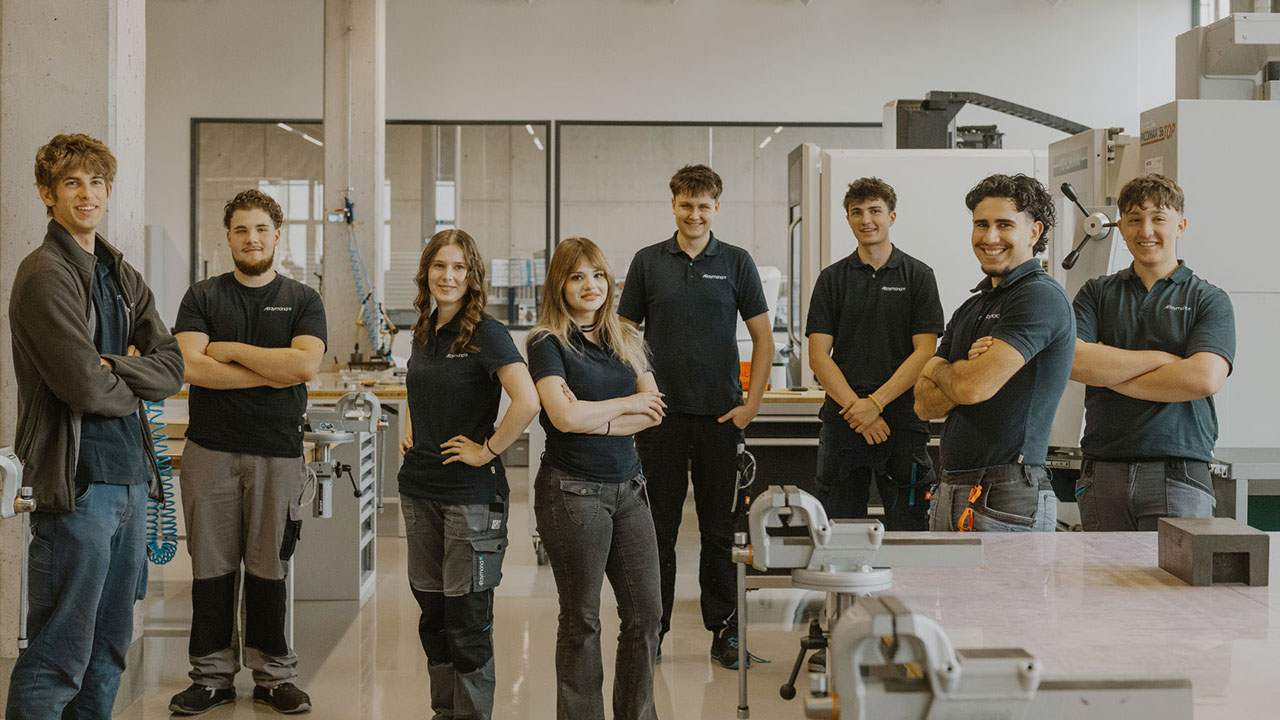 Gruppenfoto von acht Auszubildenden in der Produktionsstätte