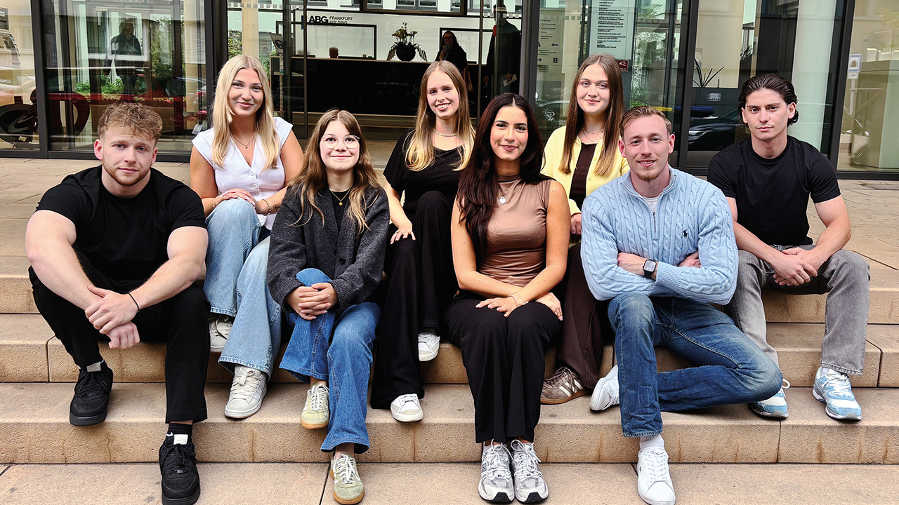 Gruppenbild: Junge Menschen sitzen auf einer Treppe vor einem Gebäude