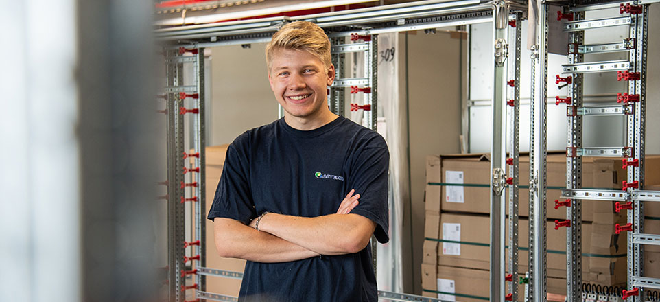 Junge lächelnde Person vor einem Lagerregal