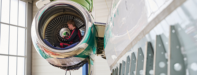 Auszubildender in einer Flugzeugturbine sitzend bei der Arbeit.