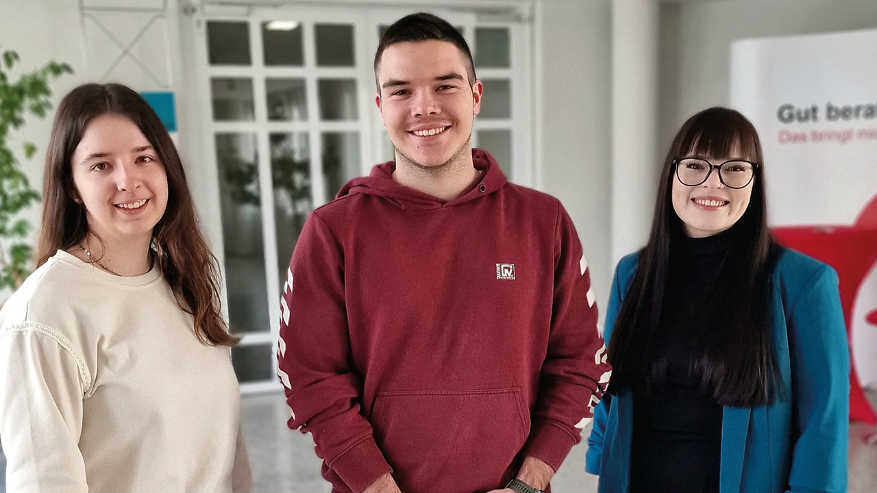 Drei Personen lächeln in die Kamera