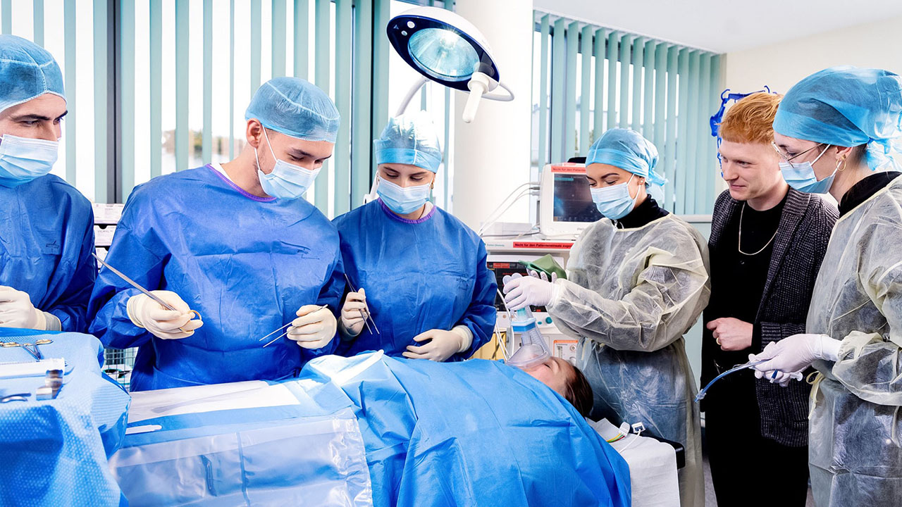 Mehrere Personen in Schutzkleidung bei der Simulation einer Operation am OP-Tisch