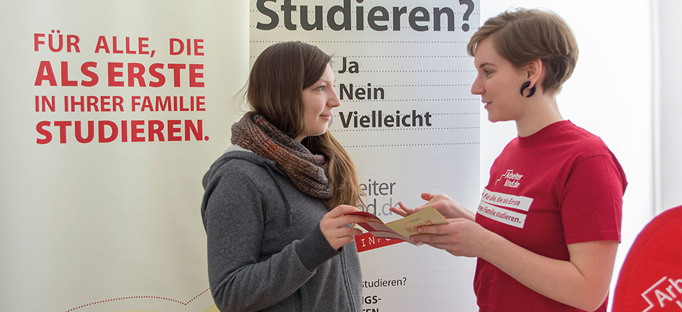 Zwei Personen unterhalten sich an einem Messestand.