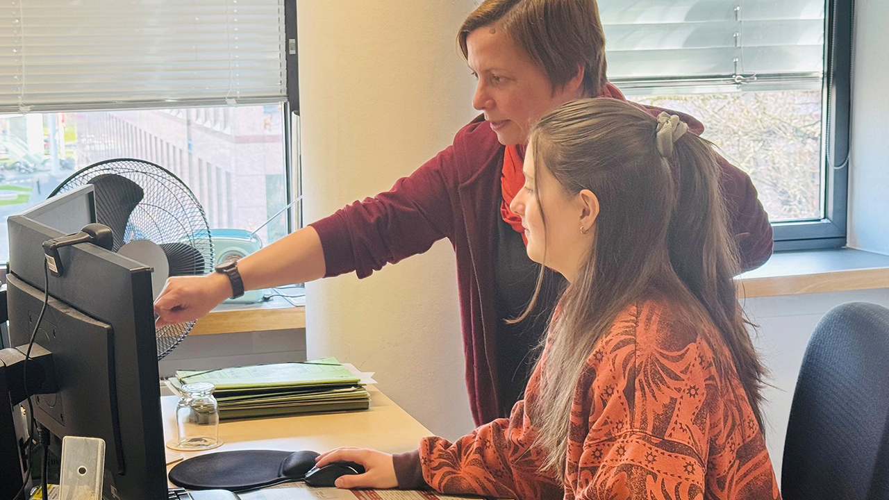 Ausbildungsszene Ausbilderin und Azubi sitzen vor einem Computer