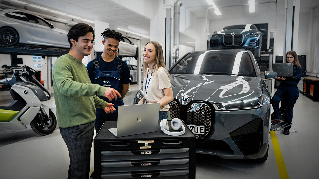 Personen an einem Laptop der in einer Auto und Motorradwerkstatt steht