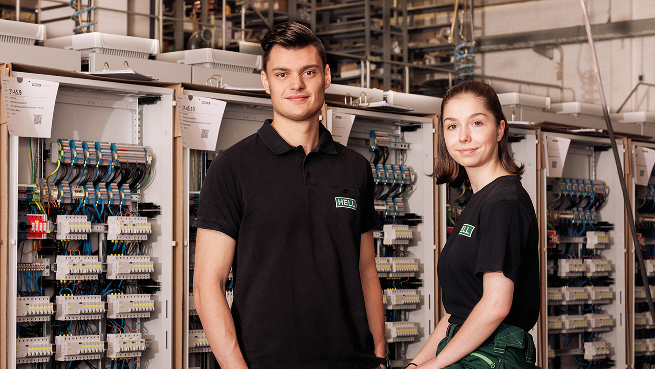 Zwei junge Mitarbeitende im Lager schauen freundlich in die Kamera