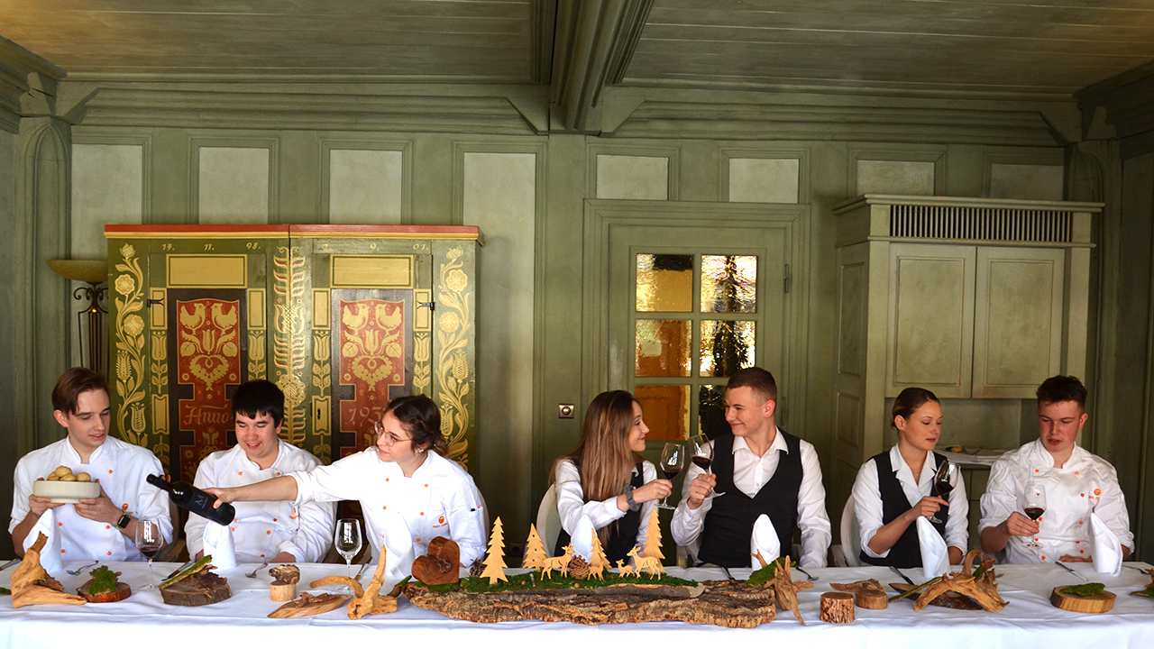 junge Menschen sitzen an einer langen Essenstafel. Es erinnert an das Bild des letzten Abendmahls