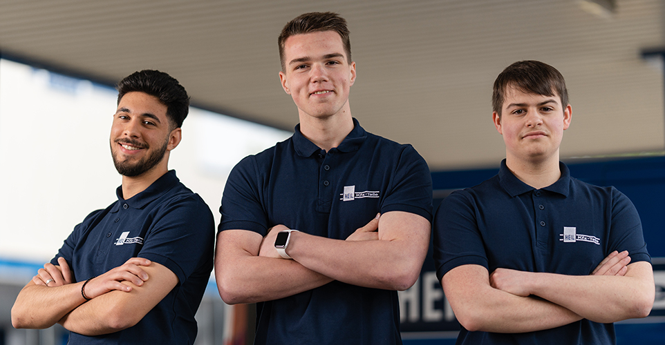 Drei Personen verschrenken die Arme und sehen in die Kamera.