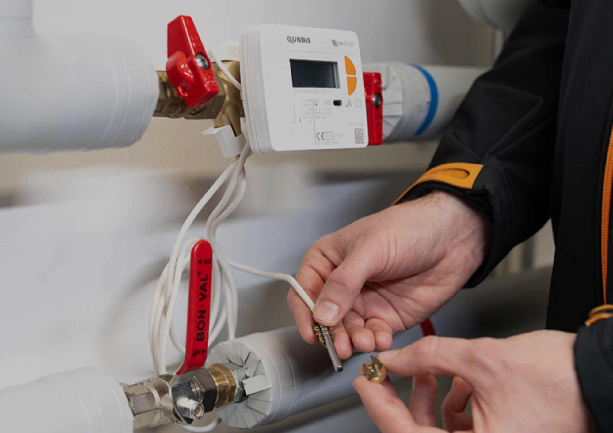 Rohre mit Messgeräten. Man sieht Hände die mit dem Messgerät arbeiten