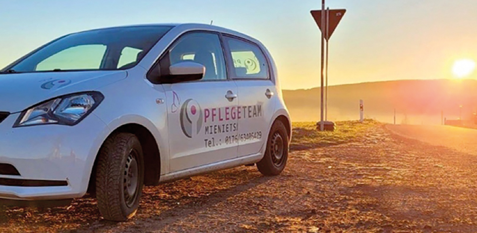 Firmenfahrzeug des Mieniets Pflegeteams im Licht der untergehenden Sonne