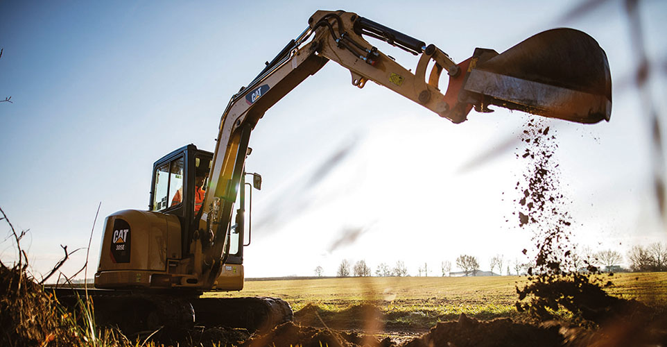 Zu sehen ist ein Bagger im Hintergrund ist ein Feld zu sehen.