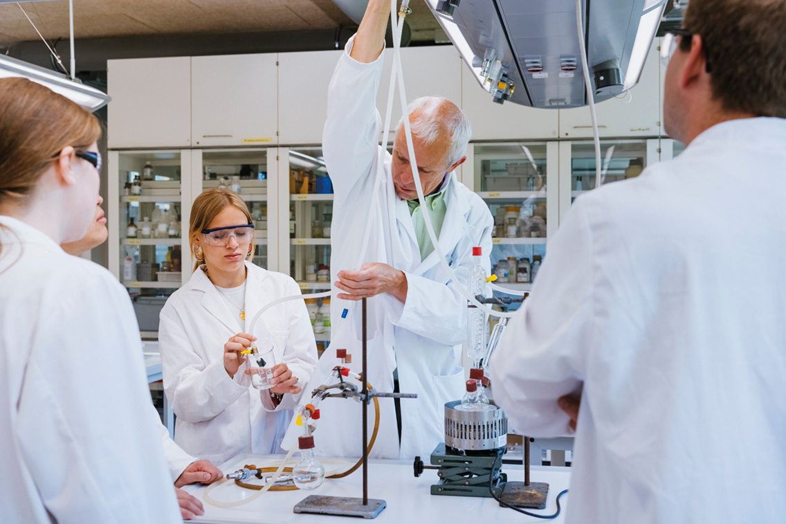 Gruppe Lehrender und Schüler/innen in einem Chemielabor