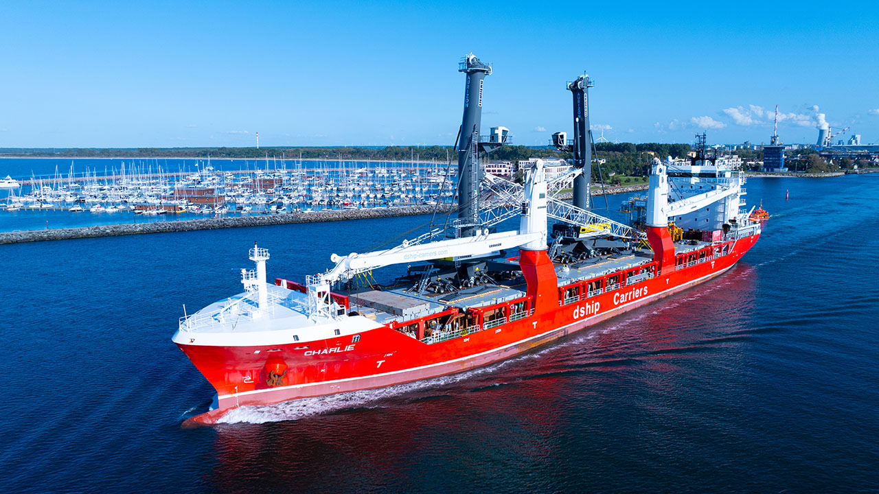 Das Bild zeigt ein rotes Schiff as aus einem Hafen ausfährt.
