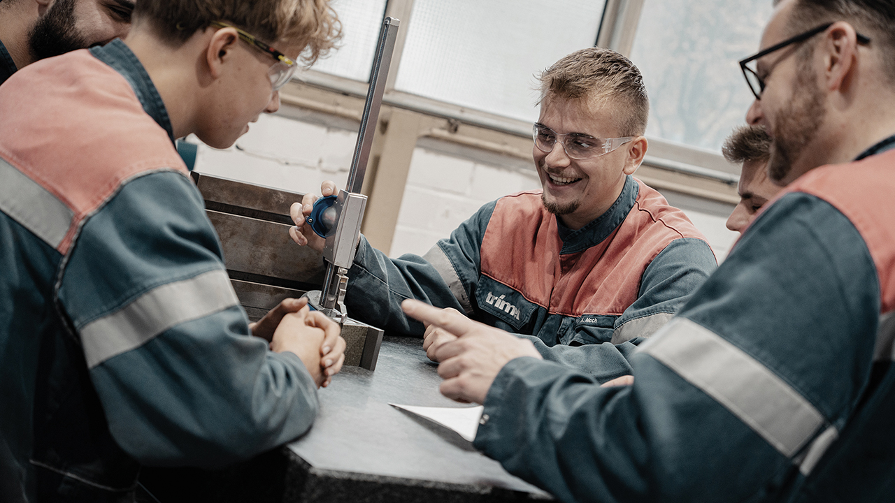 Junge Mitarbeitende in Arbeitskleidung bei der Arbeit