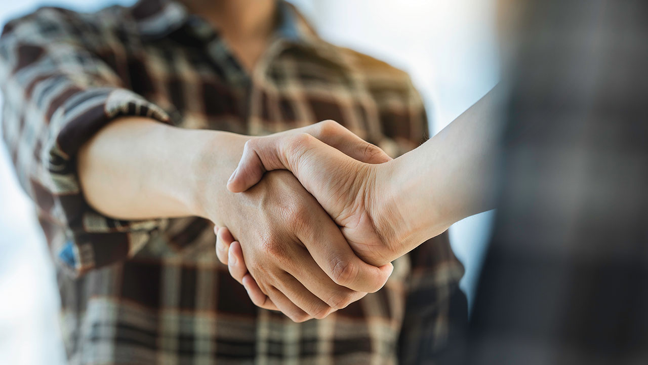 Zwei Personen geben sich einen Händedruck.