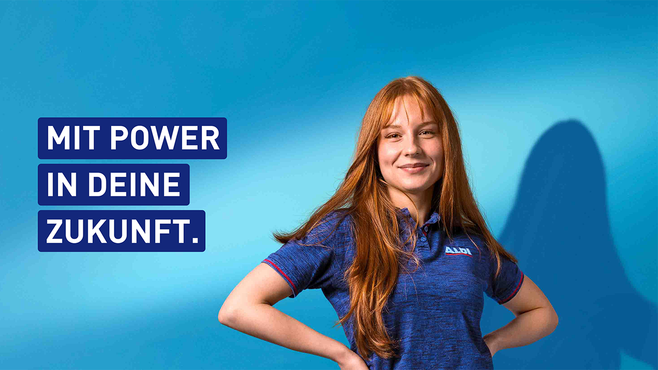Junge Frau die freundlich schaut im Aldi Shirt. Daneben der Spruch Mit Power in deine Zukunft.