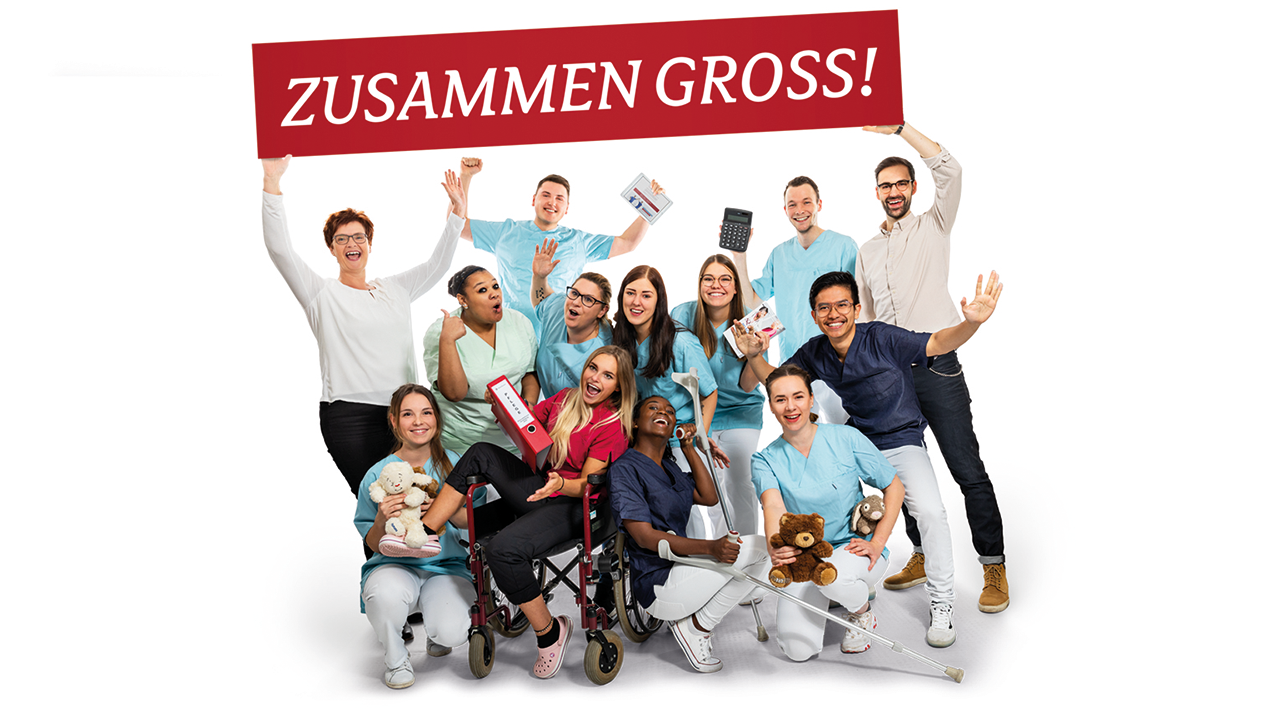 Foto einer gut gelaunten Menschengruppe in der typischen Berufskleidung von Pflegenden und Menschen die in der Verwaltung arbeiten. Darüber der Spruch: Zusammen groß!
