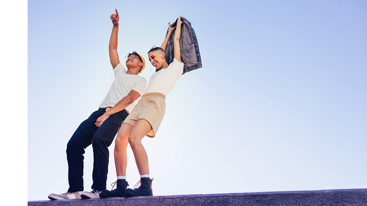 Zwei Personen stehen vor einem blauen Hintergrund und heben ihre Hände in die Luft