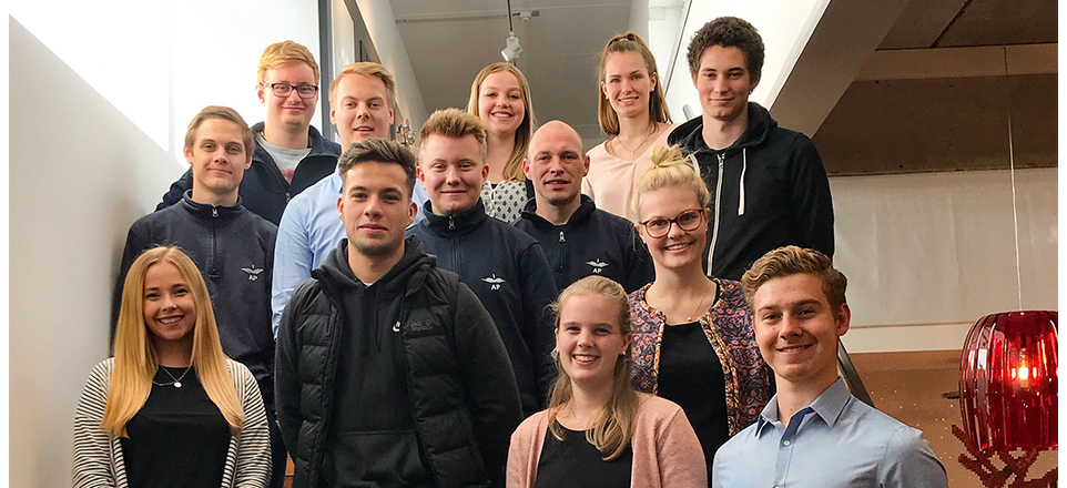 Personengruppe lächelt in die Kamera. Alle stehen auf einer Treppe.