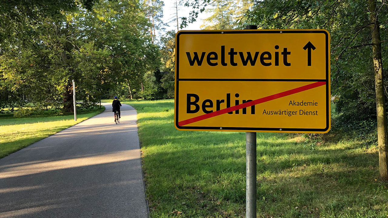 Wegweiser mit der Aufschrift Berlin durchgestrichen, weltweit mit Pfeil